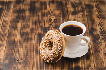White cup of black coffee and donut with nuts. Copy space.