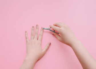 Manicure process Top view photo with copy space Girl is cutting the cuticle with nail tweezers against pink background