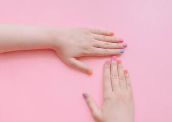 Colored manicure Top view photo with copy space Female hands with multicolored nails on light pink background