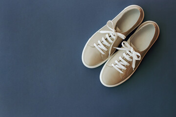 beige leather sneakers with white laces in the corner of the frame on a blue background, a place for the inscription