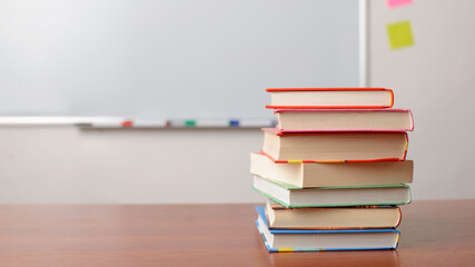Pile of books on the table with a board on the background. Education, studying concept