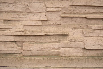The texture of the wall with a relief of uneven cream-colored stone
