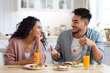 Obraz na płótnie Canvas Romantic millennial arab couple eating tasty breakfast together in kitchen at home