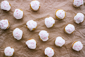 easter cupcakes with white icing and a sprinkle of pink hearts on brown crumpled craft paper, top view