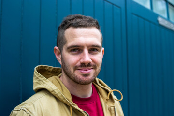 Photo of a young and attractive man looking at the camera and smiling. Stylish guy wearing informal clothes. Walk in the street