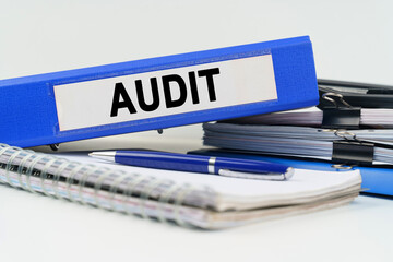 On the table are a notebook, a pen, documents and a folder with the inscription - AUDIT