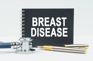 On a white background lies a stethoscope, a pen and a black notebook with the inscription - BREAST DISEASE