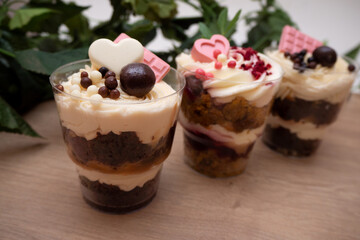 Sweet small homemade trifle dessert with custard, chocolate, nuts and fruits and decorations and cream cheese.