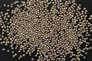 background of buckwheat groats scattered on black paper