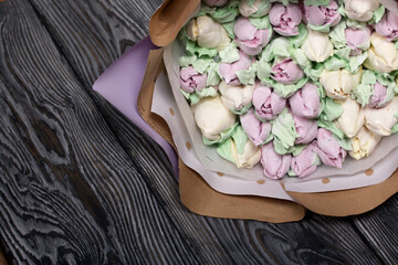 Zephyr bouquet. Marshmallow tulips are collected in a bouquet and wrapped in craft paper. Lies on pine boards.