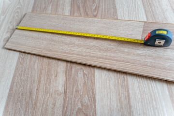 Measuring Laminate Wooden Floor Board with Yellow Measure Tape for Room Reconstruction