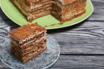 Honey cake decorated with zephyr tulips. The piece is cut off. On pine boards.