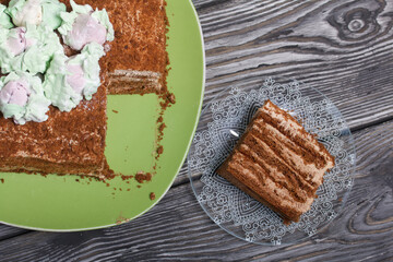 Honey cake decorated with zephyr tulips. The piece is cut off. On pine boards.