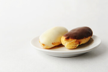 Two eclairs on a white saucer on a white background isolated. Free space