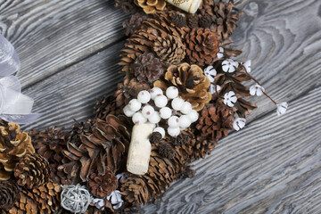 A wreath of cones, wine corks and decorative elements. Lies on pine boards. Close-up shot.
