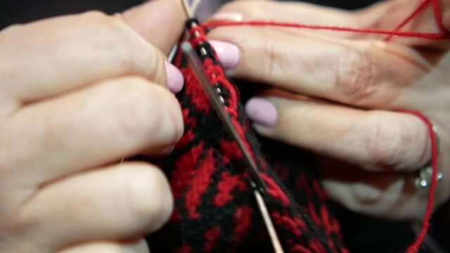 close-up of knitting woolen socks in the traditional way, hand knitting woolen socks with traditional ornaments, woman's hands with needles knitting socks, tardicional serbian woolen socks, old craft