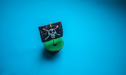 A walnut shell boat with a pirate flag on a blue background.