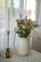 Trendy white home deccoration - flower bouquet and two candles 
