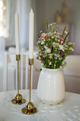 Trendy white home deccoration - flower bouquet and two candles 