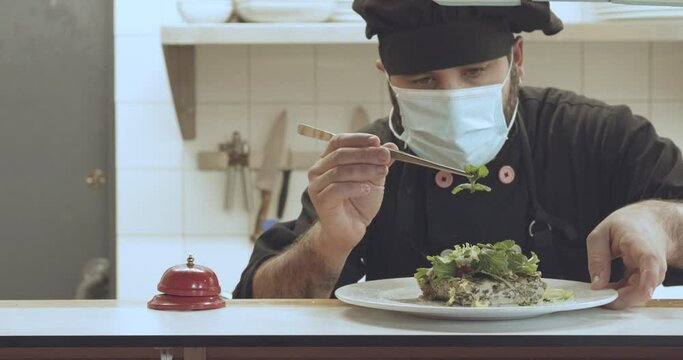 Detail of a cook with a medical mask decorating a vegan dish in a Spanish restaurant