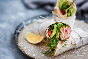 Fresh and healthy wrapped tortilla with crab salad, cucumber, avocado, pepper and green herbs