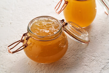 Cool congealed beef bone broth in two glass jars on a bright background