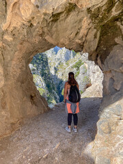 Cain, Spain - September 1, 2020: Female hiking trough the Cares Route in the heart of Picos de Europa National Park, Spain. Narrow and impressive canyon between cliffs, bridges and footpaths.