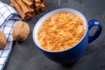 Blue cup of salep milky hot drink of Turkey with cinnamon powder and sticks healthy spice rustic vintage wooden table.