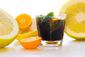 Glass with a fresh still soda drink surrounded by citrus fruits, summer freshness concept