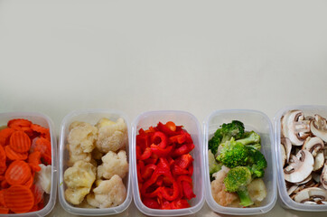 Trays with raw vegetables for freezing. Stocking up for winter storage in plastic containers, puts in a box to freeze red bell peppers, broccoli, cauliflower, carrots