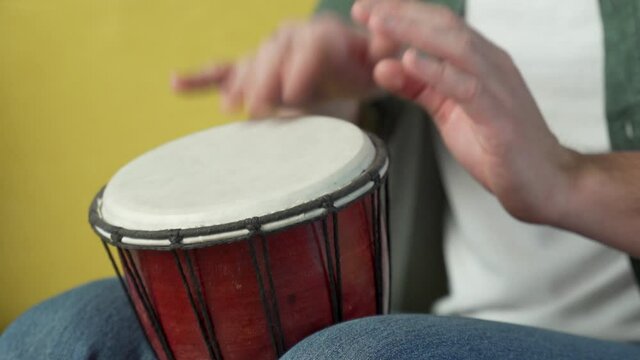 Male hands tapping djembe, bongo in rhythm. Musical handmade instruments