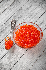 Red caviar in a crystal bowl on a black background. Delicacy product of the highest quality.