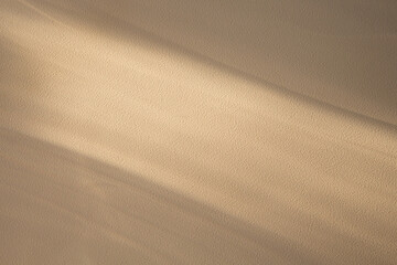 Diagonal natural shadow on a sand color textured wall. Copyspace with place for text. Summer seasonal concept for background, product presentation, mockup, photo, posters and wallpapers. Minimalism.
