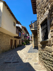 Puebla de Sanabria, Spain - September 6, 2020: Cobblestone street with picturesque stone residential buildings and flowered balconies in Puebla de Sanabría, Zamora province, Castilla y León.