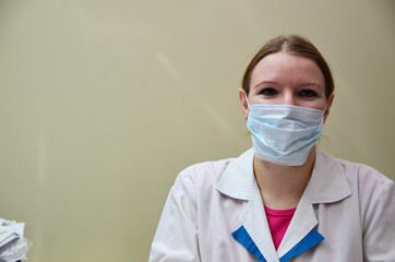 Portrait of female doctor in special surgical sterile protective clothing. puts on a mask and gloves before receiving a patient in the office