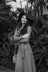 Waist-up portrait of young woman wearing knitted dress and wide-brimmed hat