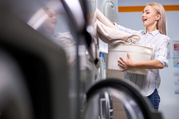 Housework: woman loading clothes into washing machine. caucasian lady enjoys cleaning process....