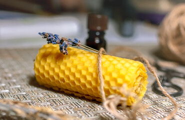 Closeup yellow decorative wax candle.A dropper bottle of lavender essential oil , scissors and jute. Selective focus, horizontal.