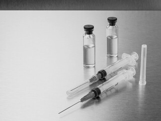 Syringes and ampoules on a polished metal background. Coronavirus vaccination and immunization...