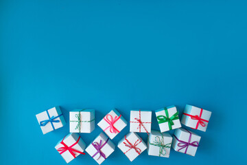 White boxes with colored ribbons lie on a blue background. Top view. Space for the text.