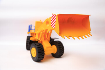 Scale model of a yellow single-bucket loader on white background