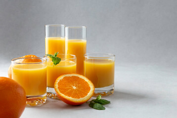 Fresh oranges and 100% orange juice in glasses on an gray background. Close-up. Copy space. Detox