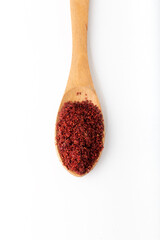 Dried red pepper flakes in the wooden spoon on white background.