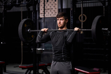 Naklejka na ściany i meble sportsman lifting barbell in cross fit gym, bodybuilding and weightlifting concept. male in sportswear engaged in crossft workout, training alone