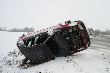 Difficult winter snow condition car accident concept, car lying on its side after hard crash