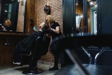 Fototapeta na wymiar Client during beard shaving in barber shop