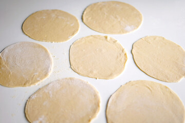 circles on dough on a white table for chebureks