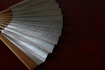 漆塗り板背景の銀色の扇子