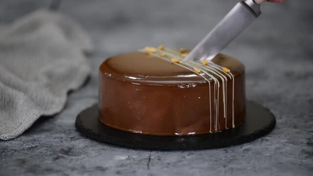 Cutting a chocolate caramel peanut mousse cake and mirror glaze.