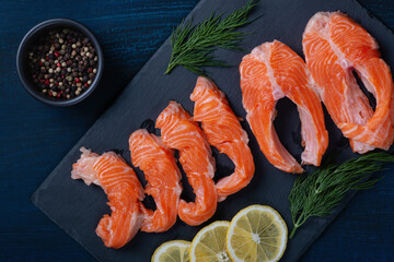 Salmon. Fresh raw salmon fish fillet with cooking ingredients, herbs and lemon on blue background, top view